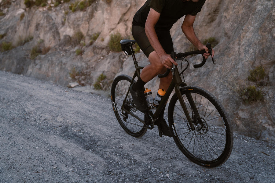 A man riding a black bike, showing close up of Continental brand tyres on a gravel road.