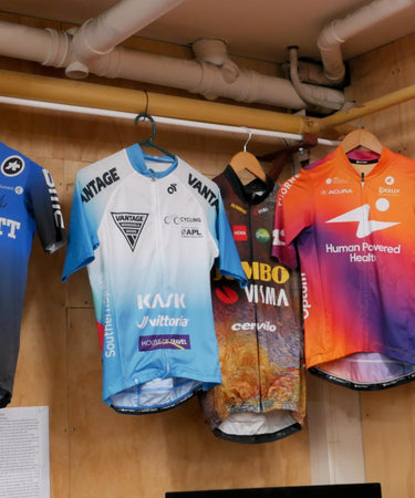 Different coloured riding shirts/ tops hanging on the wall for decor inside Velo Workshop.